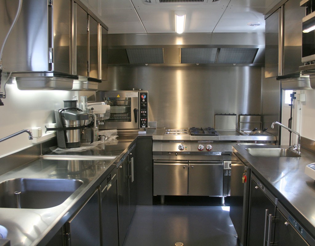 Vue générale de la cuisine : zone laverie à gauche, cuisson au fond et préparation à droite